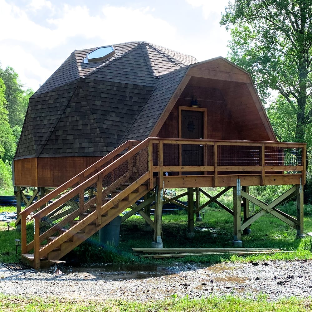 A geodesic dome raised on stilts among the trees